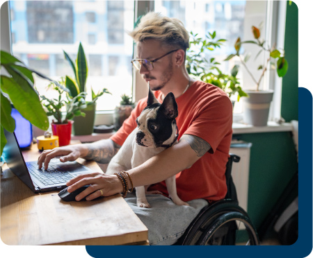 Nonprofit employee working at a computer with a dog on his lap.