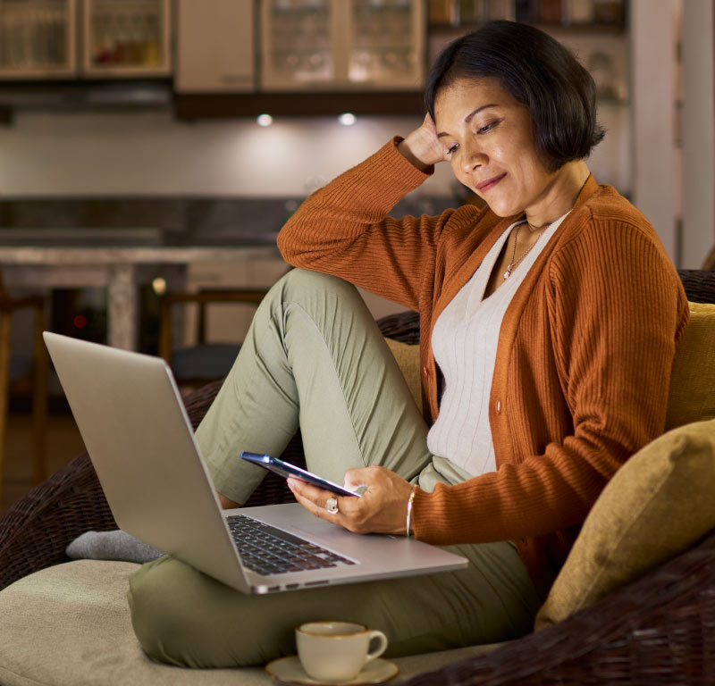 woman on computer and phone smiling