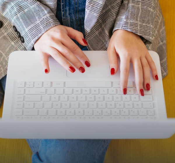 woman with red nails typing on white laptop