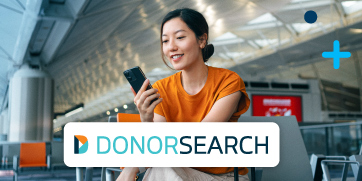 A woman holding a phone in an airport with the DonorSearch logo in foreground