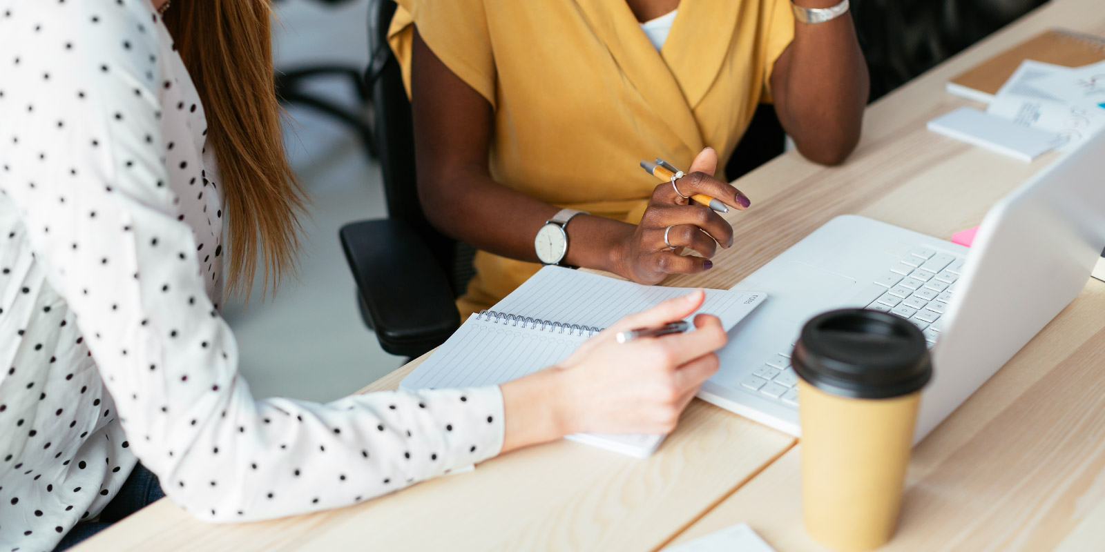 Close up of two people working at a desk. 