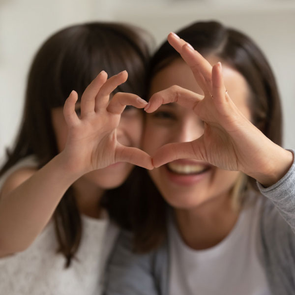Two girls making a heart with their hands together