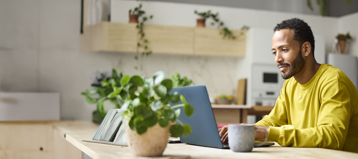 Confident young freelancer using laptop. Male is working from home. He is sitting at table.