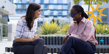 Two women sitting outside engaging in conversation.