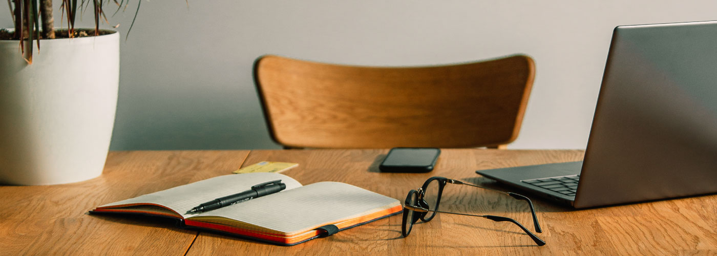 Work place with table, chair, laptop, plant, phone and notepad