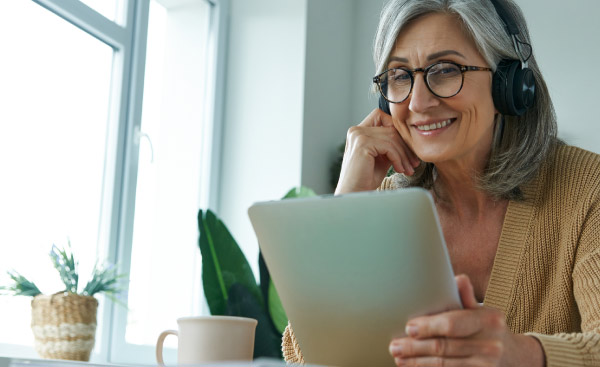 Cheerful senior woman using digital tablet while working from home