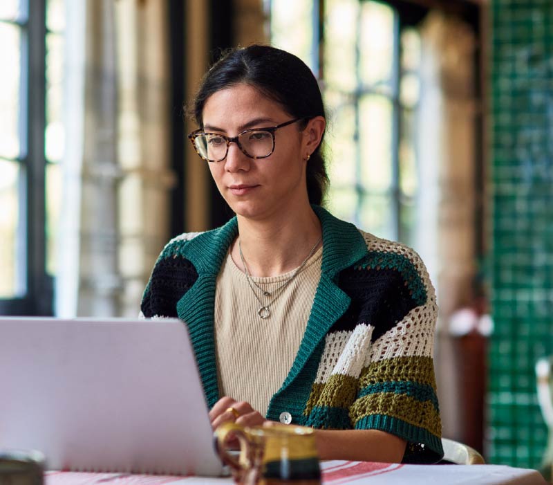 Woman in her 30's working from home sitting at table in dining room using laptop, home office, concentration, connection, working from home