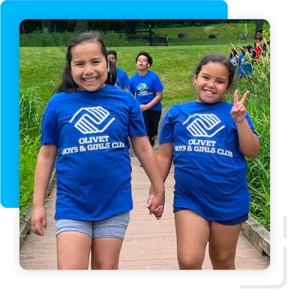 Two young girls wearing Olivet Boys & girls Club t-shirts and smiling to the camera.