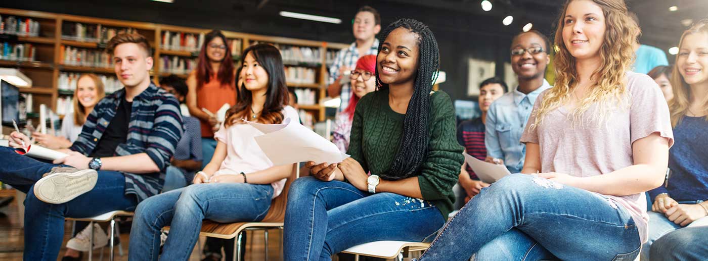 Group of young adult students sit in a classroom.