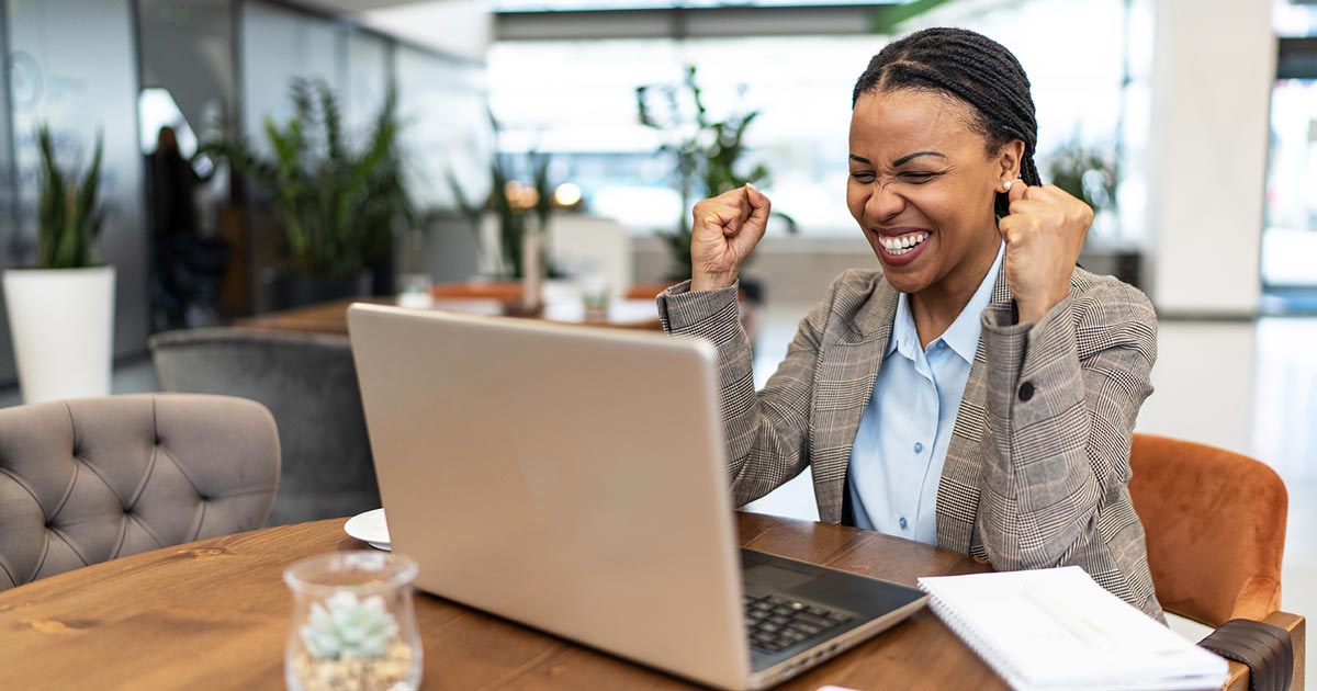 Image of a woman celebrating while working on a computer