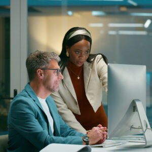 Two people working on the computer together in an office