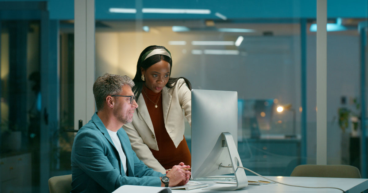 Two people working on the computer together in an office