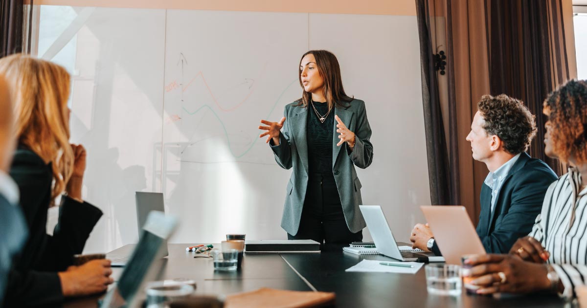 Female business entrepreneur explaining strategies to colleagues in board room at office