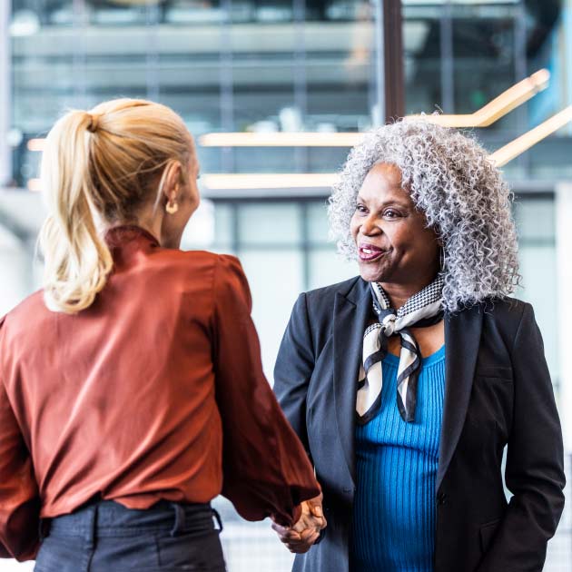 Female business colleagues shaking hands in modern business lobby