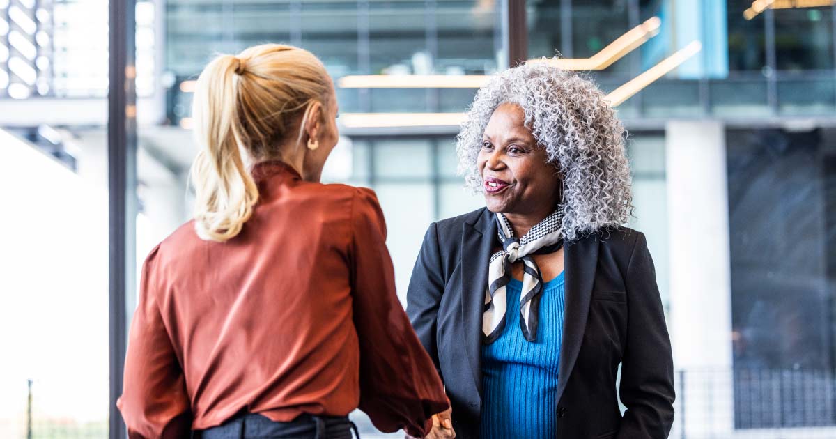 Female business colleagues shaking hands in modern business lobby