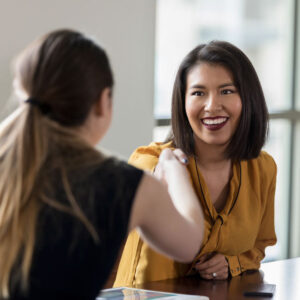 Cheerful mid adult businesswoman greets a colleague with a handshake before a meeting.