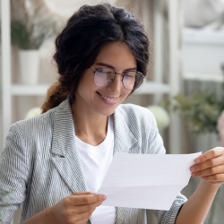 Woman opening a check while smiling in her office.