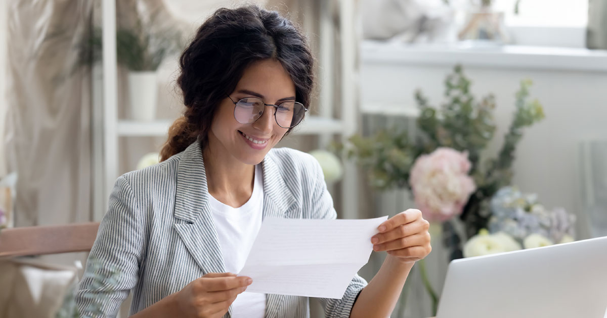Woman in an office smiling while looking down at a cheque