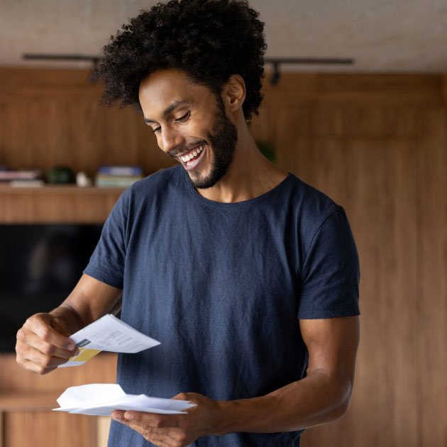 Man standing in his living room excitedly reading a letter from a nonprofit