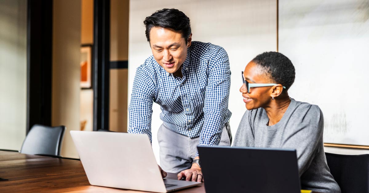 Business colleagues working on laptops in modern conference room