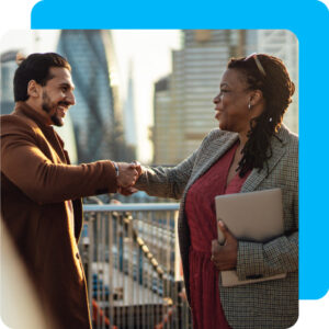 Woman and man shaking hands with a city-scape in the background.