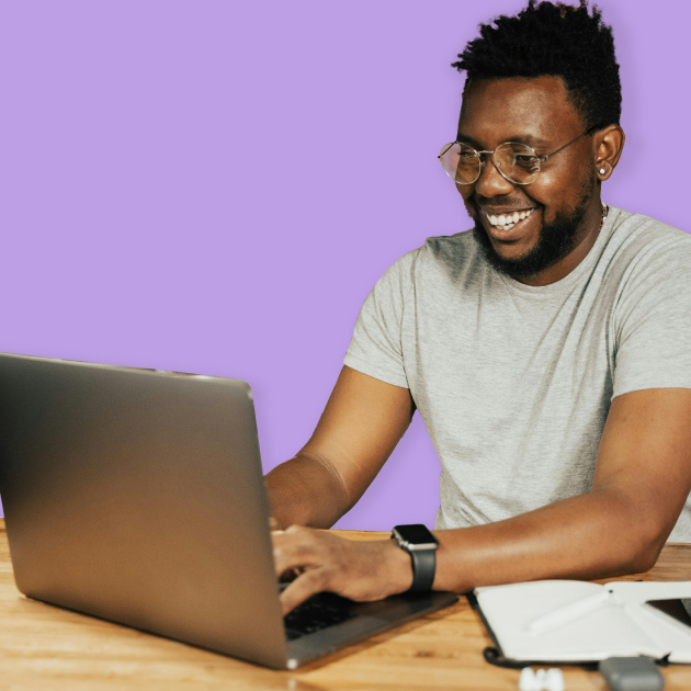 A smiling man using a laptop, embodying joy and engagement in his digital tasks.