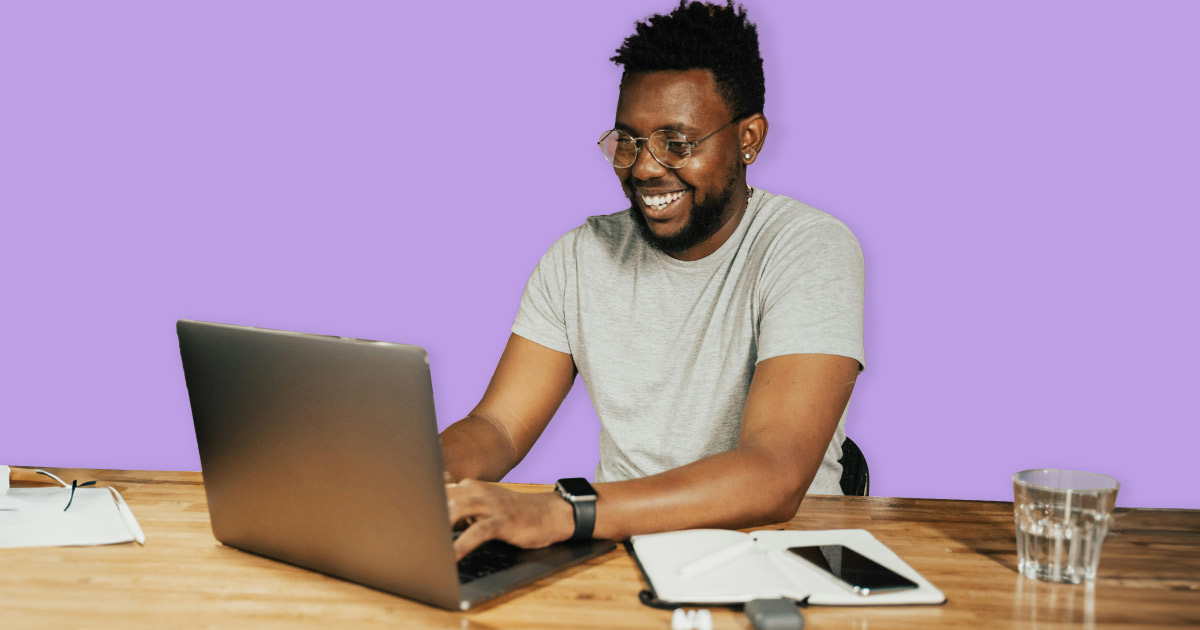 A smiling man using a laptop, embodying joy and engagement in his digital tasks.