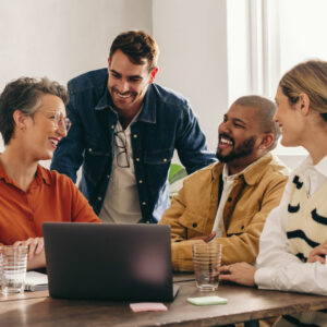 A few coworkers looking at a computer while laughing together in the office.