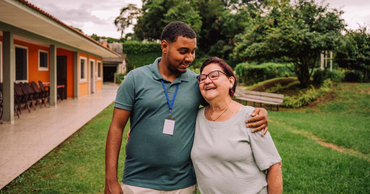 Volunteer walking in garden with elderly woman in nursing home