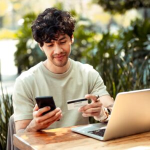 Young man sitting at the cafe and paying online with credit card