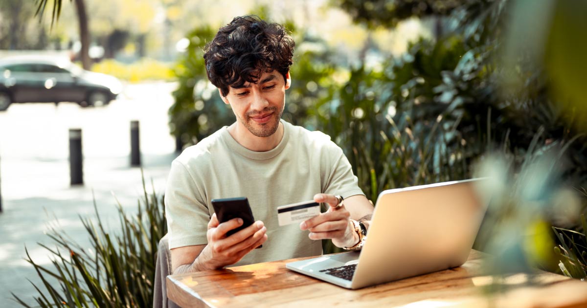 Young man sitting at the cafe and paying online with credit card