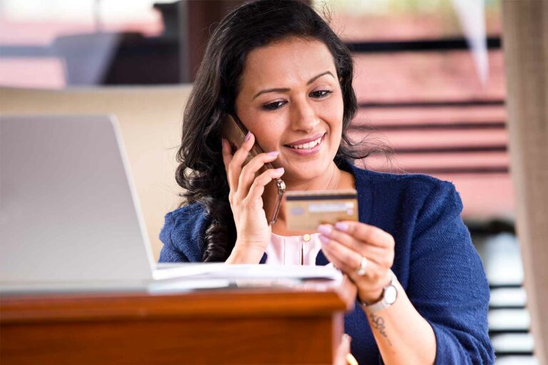 Woman looking at credit card while talking on phone