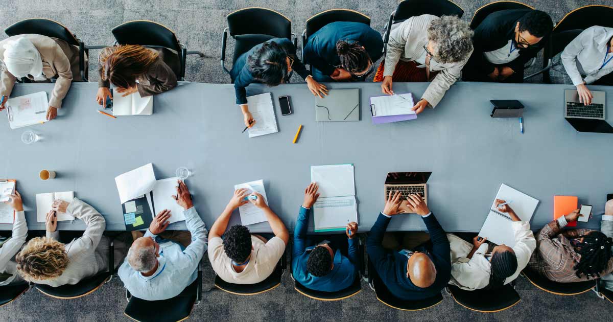 Overhead shot of business panel in office meeting collaborating around large table