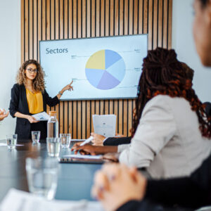 Businesswoman leading business meeting using statistics chart on presentation TV