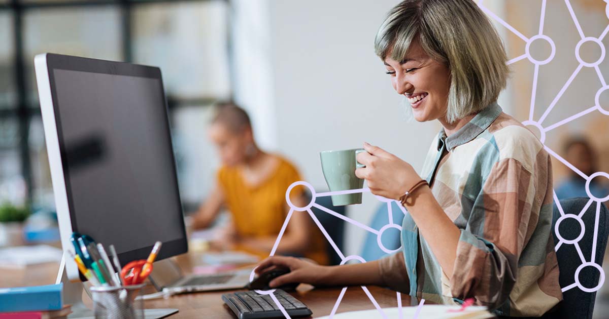 Woman holding a cup of coffee while working at an office.