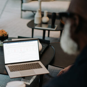Coworkers look at a laptop together as they drink takeaway coffees