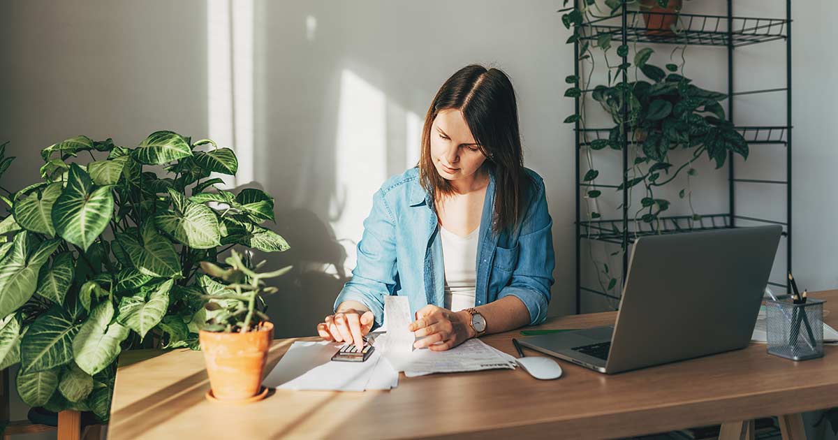 Top view close up woman calculating bills, money, loan or rent payments, using laptop, online banking service, sitting at table, female holding receipt, planning budget, managing expenses, finances
