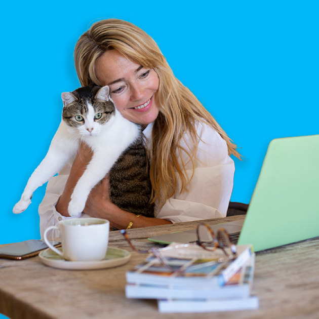 Woman holding her cat reading a welcome email on her green laptop.