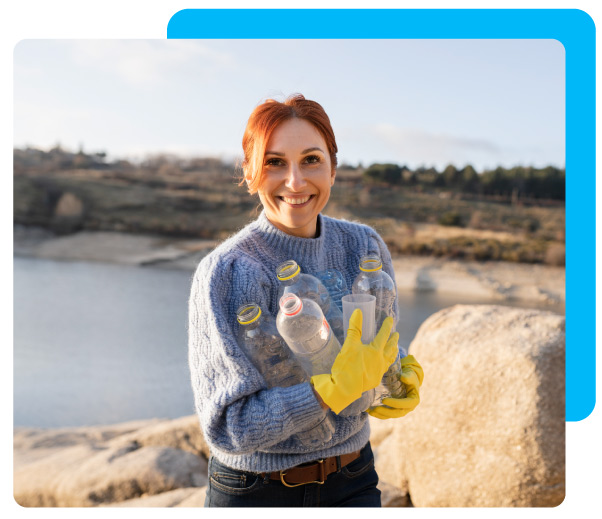 Volunteer collecting bottles on beach and smiling