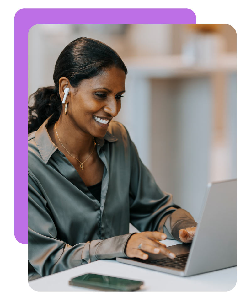 Smiling mature businesswoman using laptop while sitting at desk in office